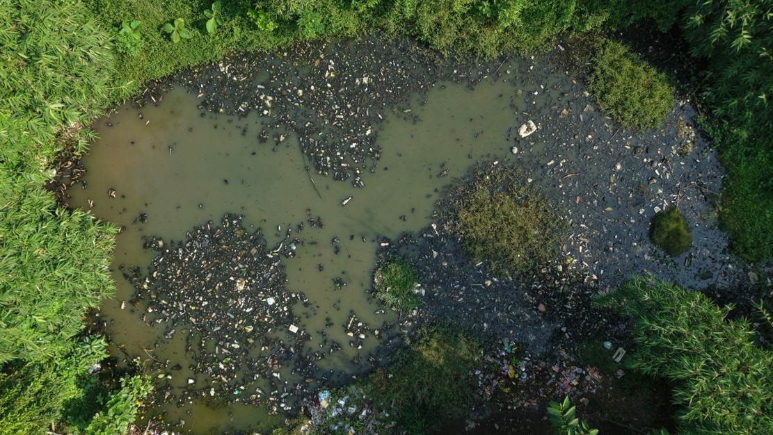 Unsanitary street before All Out initiative with garbage and stagnant mosquito breeding pool